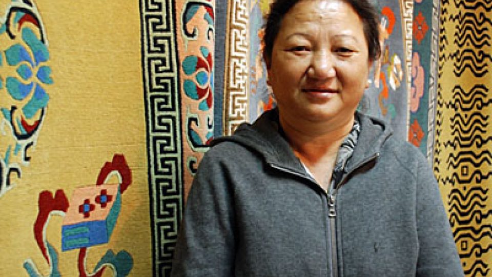 Tibeťanka Amrita před tibetskými koberci