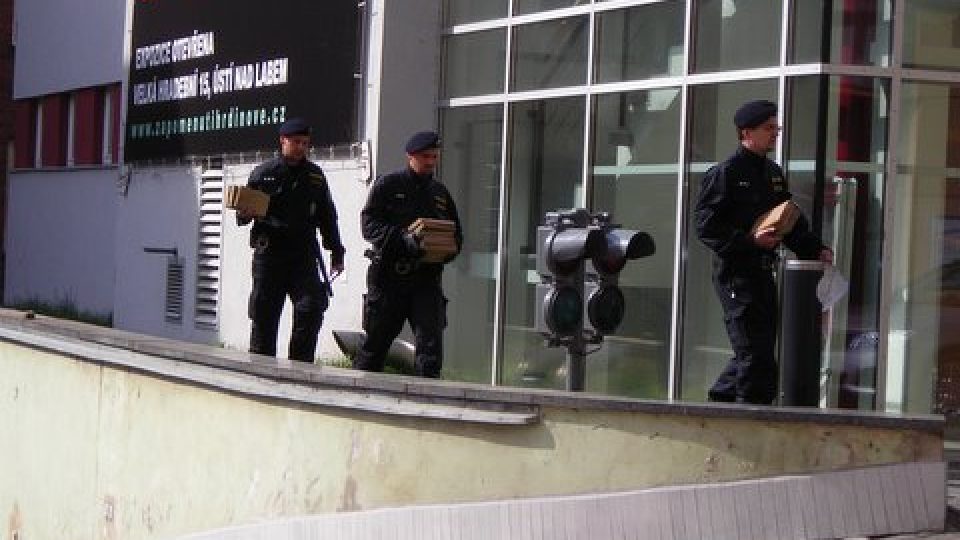 Policisté odnášejí stavební materiál, který by mohl posloužit jako munice