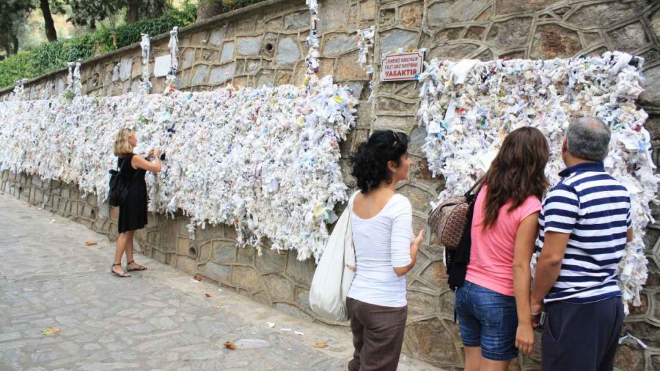 Poutníci i turisté připevňují papírky se svými přáními na zeď u Domu Panny Marie