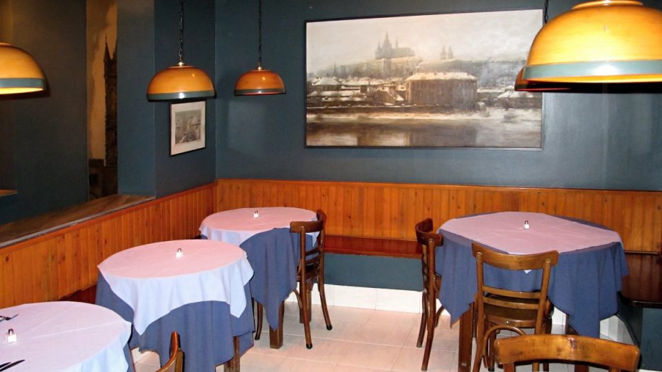 V restauraci Spirose Kulurise v centru většinou rozpálených Athén čeká na návštěvníky silueta Hradčan a zasněžená Praha