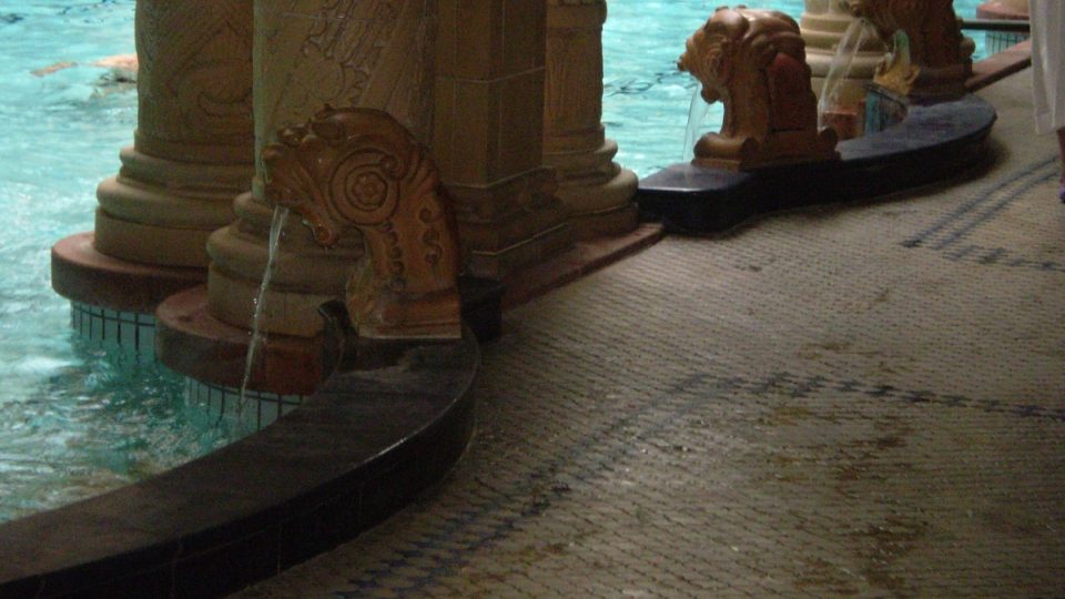 Termální voda natéká do bazénu přes nádherně vypracované lví hlavy