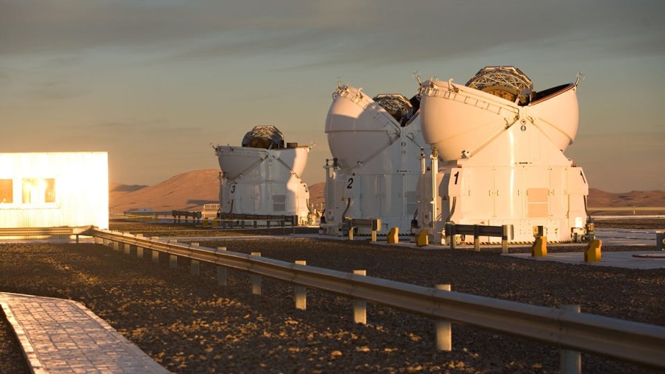 Tři ze čtyř pomocných teleskopů observatoře Paranal během otevírání při západu slunce