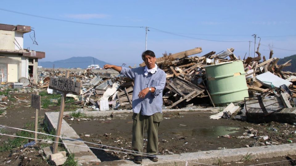 Pan Kanno ukazuje na zbytky svého domu ve zničeném městě Rikuzen Takata