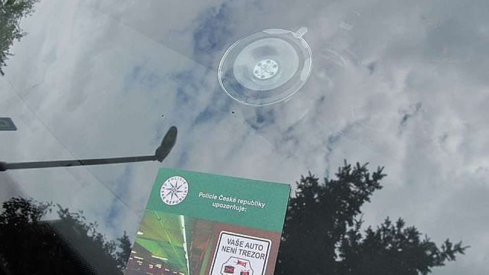 Přední sklo zaparkovaného automobilu s upozorněním od Policie ČR že "Vaše auto není trezor"