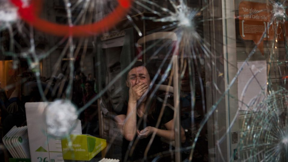 Mireia Arnau pláče kvůli sklu výlohy, které poškodili demonstranti během střetu s policií v Barceloně