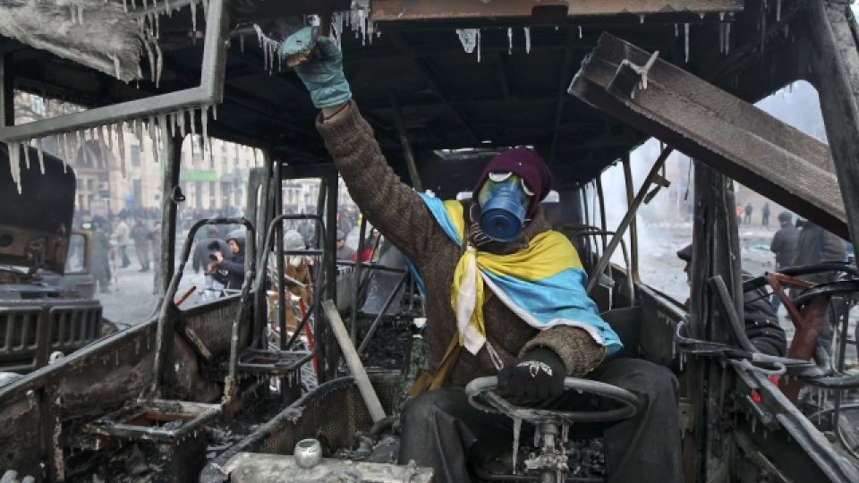 Ukrajina, Kyjev. Proevropský demonstrant ve shořelých troskách policejního autobusu 