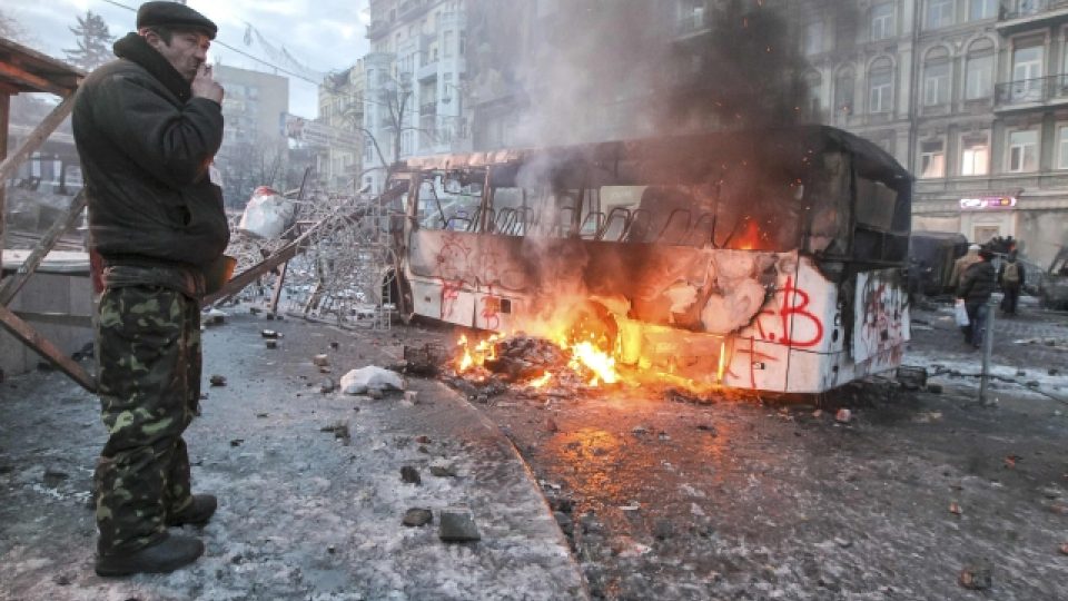 Ukrajina, Kyjev. Muž kouří nedaleko trosek policejního autobusu