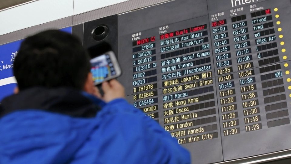 Muž na pekingském letišti si fotí informační tabuli s přílety, malajsijské letadlo tam mělo přistát už před půlnocí SEČ