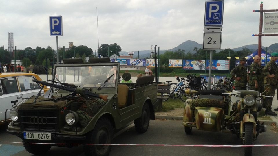 Před řopíkem stojí vojenská vozidla