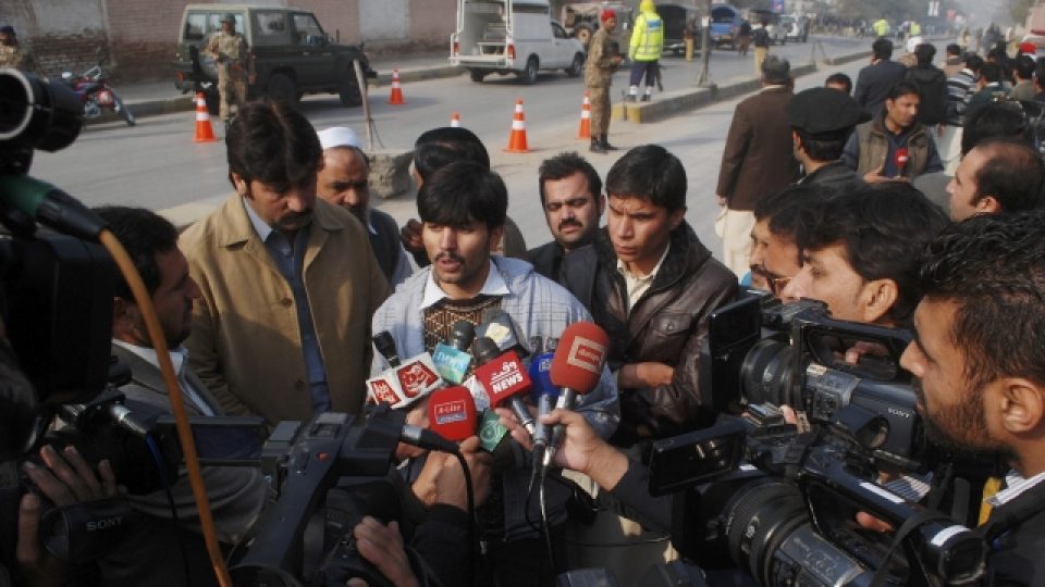 Novináři zpovídají muže, kterému se podařilo dostat z budovy školy