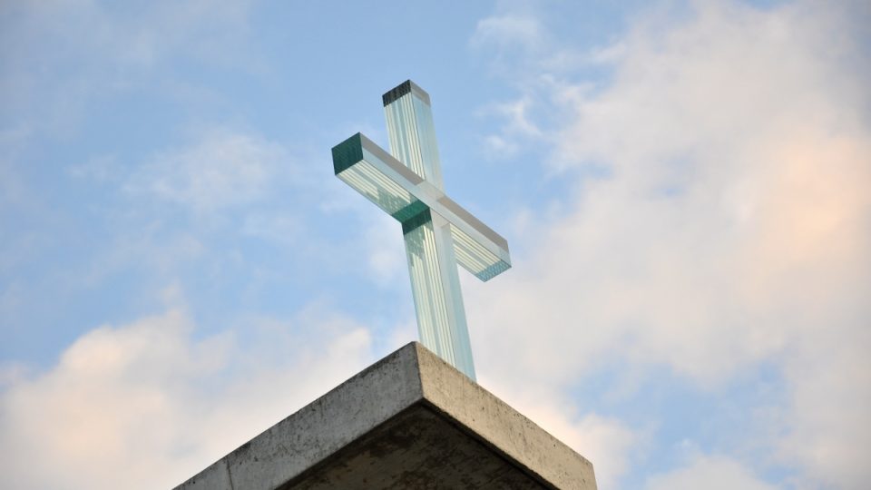 Prodloužená střecha nad hlavním vstupem vrcholí křížem z vrstveného optického skla