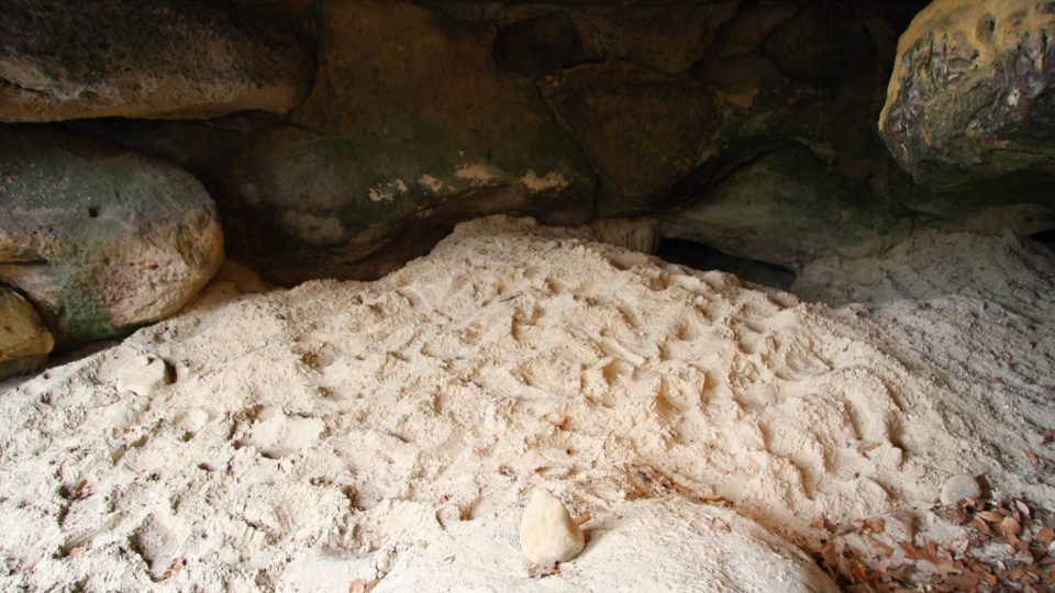 Zdevastovaná jeskyně. Hromadu písku hledači vytěžili ze zadních částí a plazivkových tunelů