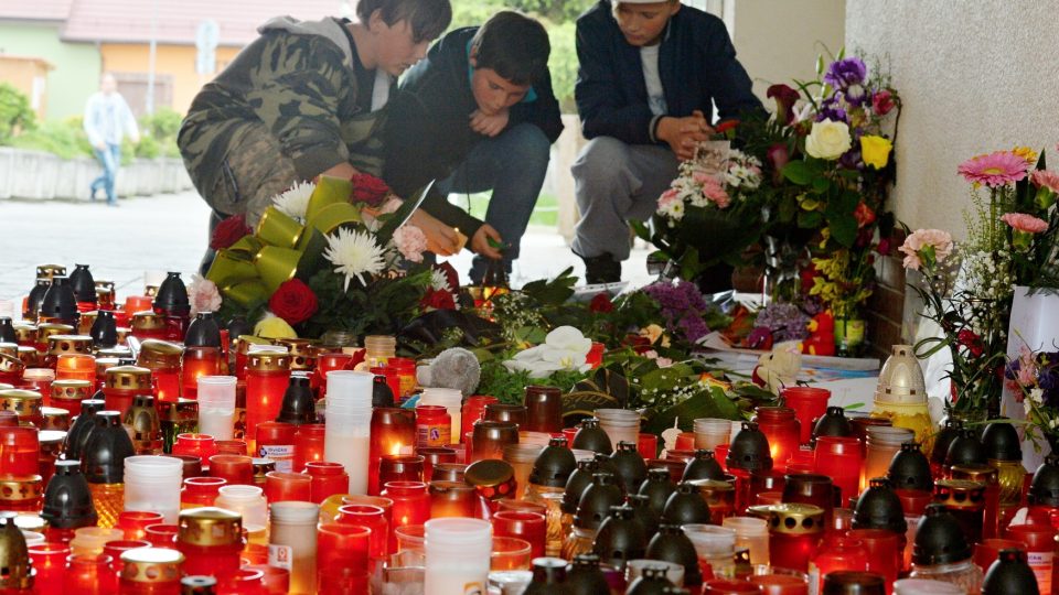 Pietní místo před dveřmi knihovny, kde přibývají květiny, dětské kresby a svíčky