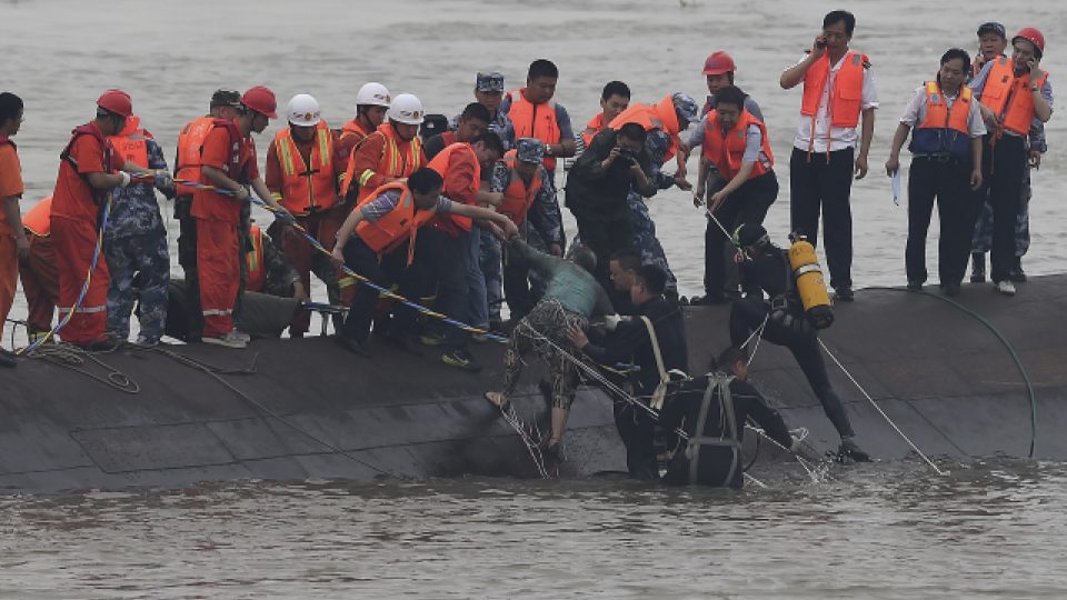 Záchranáři pomáhají pasažérům, kteří byli uvezněni v trupu lodi. Mnoho lidí je stále nezvěstných
