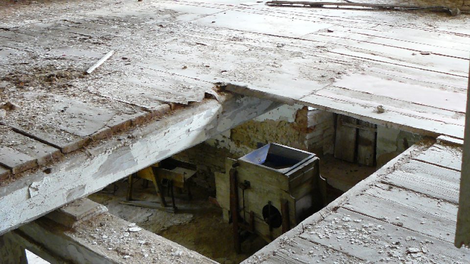 Pohled do pžízemí skrz díru v podlaze v prvním patže sušárny