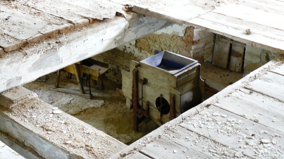 Pohled do pžízemí skrz díru v podlaze v prvním patže sušárny