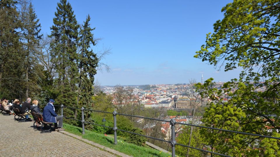 Turisté sedí na petřínských lavičkách a kochají se krásou Prahy