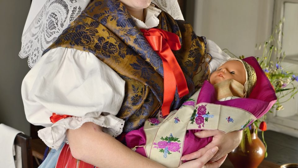 Křestní oděv dítěte v prostředí plzeňského venkova v 19. století tvořil brokátový čepeček, košilka a barevná hedvábná peřinka, převázaná povijanem z hedvábné stuhy. Ke křtu dítě nosila kmotra
