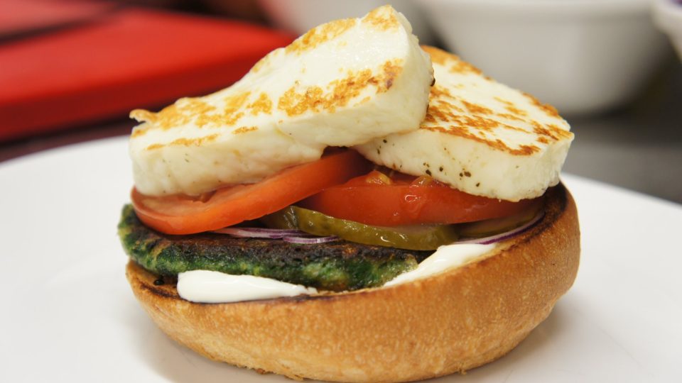 Mezi bulky dáme zeleninovou placku, sýr halloumi, plátek rajčete, cibuli a kyselou okurku