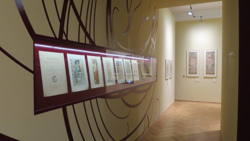 Rozevláté linie a vlasy zdobí stěny expozice plakátů Alfonse Muchy