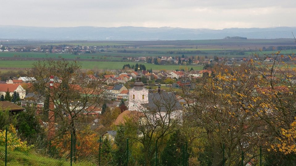 Přímo z vrcholu Malého Kosíře je výhled stíněný stromy, z úbočí je kotlina Moravy a Slatinice v popředí jako na dlani