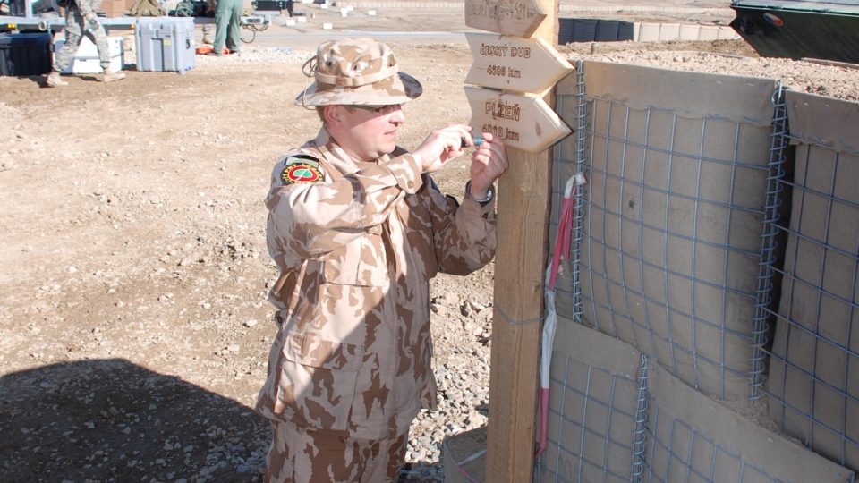  Major Jindřich Plescher přidělává ukazatel vzdálenosti do Plzně (4810 km) na rozcestník. Základna Shank, Afghánistán 2009