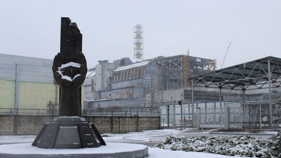 Černobyl je plný pomníků. Tento z roku 2006 nesoucí nápis "Těm, kdo zachránili svět" stojí hned před tzv. starým sarkofágem (budova v pozadí), pod nímž je pohřben havarovaný 4. blok