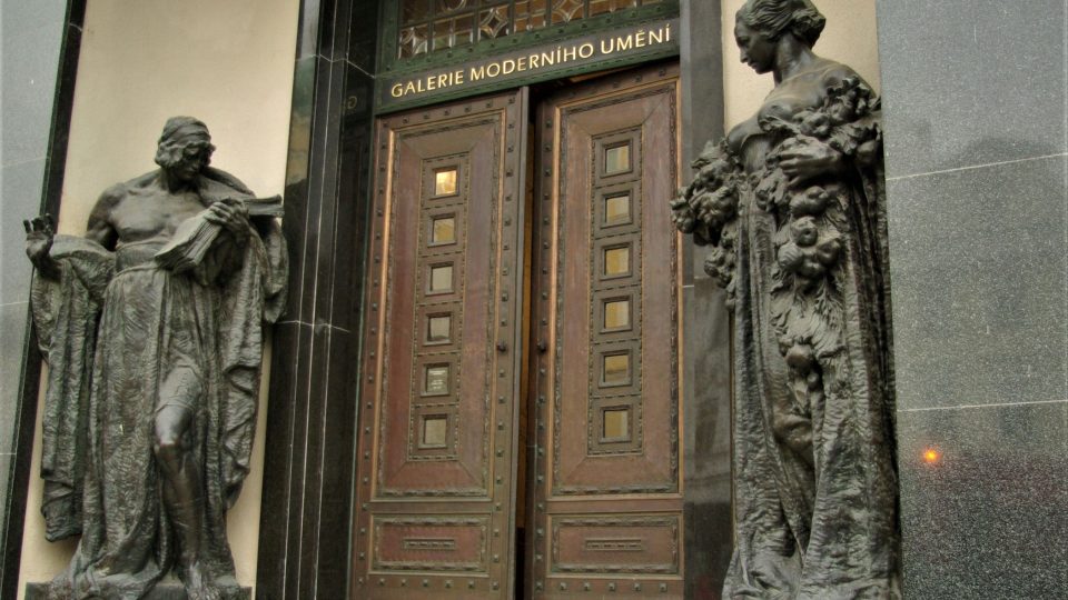 Vstup do historické budovy zdobí  Šalounovy sochy - ženská postava vpravo symbolizuje úrodu, socha muže je alegorií obchodu