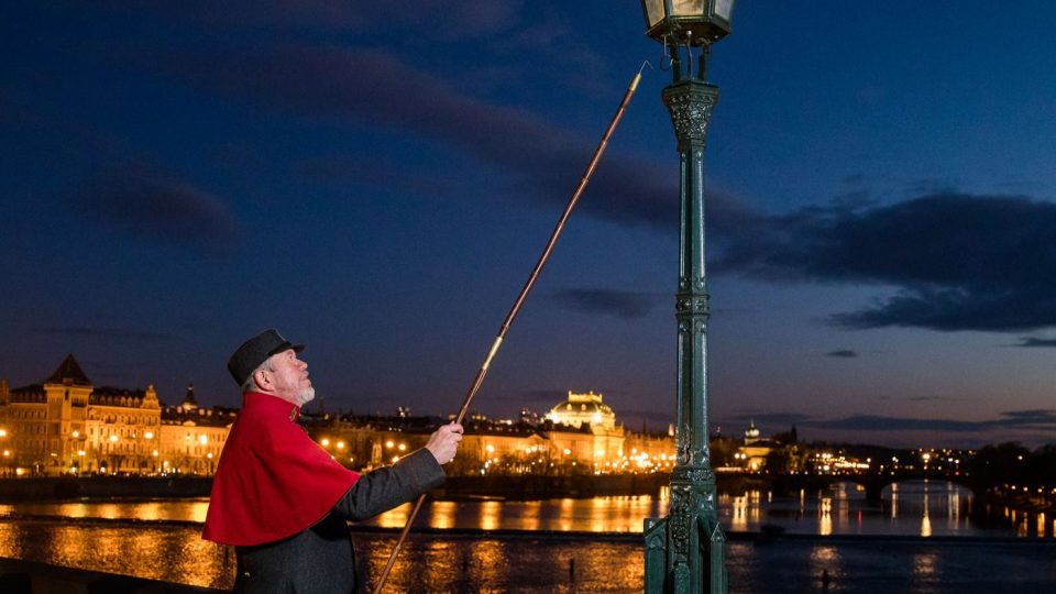 Jan Žákovec v roli lampáře rozsvěcuje plynovou lampu na Karlově mostě