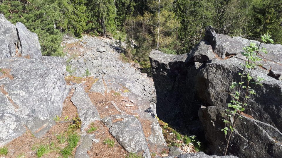 V tmavém místě průrvy ve skále je možné vidět poslední skobu horolezecké trasy na vrchol skály